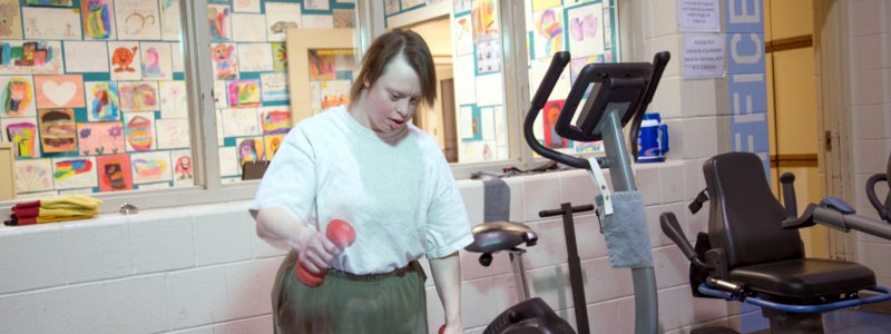 Photo of someone in a white t-shirt exercising in a gym.